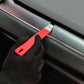 Red automotive pry bar tool used along car door seam next to gloved hand.