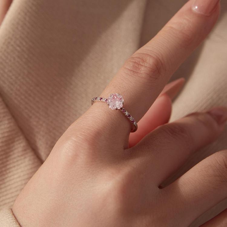 Pink cherry blossom zircon ring on a hand, with magenta stones on the band