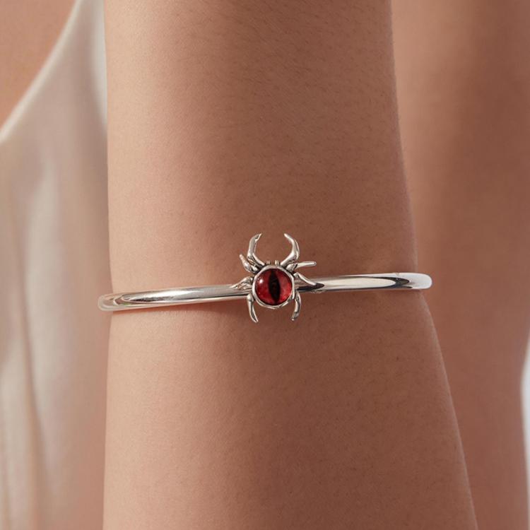 Sterling silver spider eye bracelet on wrist with red oval cabochon center