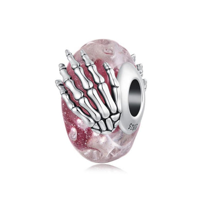 Pink glitter glass bead charm with silver skeleton-hand design and round core hole