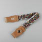 Kids elastic belt with tan snap tabs and black fabric strap with multicolor star pattern.