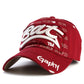 Red baseball cap with white embroidered letter pattern and curved brim