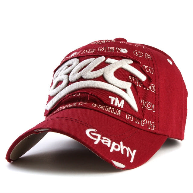 Red baseball cap with white embroidered letter pattern and curved brim