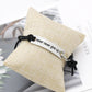 Black cord bracelet with silver bar clasp and “never never give up!” lettering