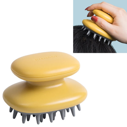 Yellow silicone scalp massage shampoo brush with gray bristles, held in hand on hair