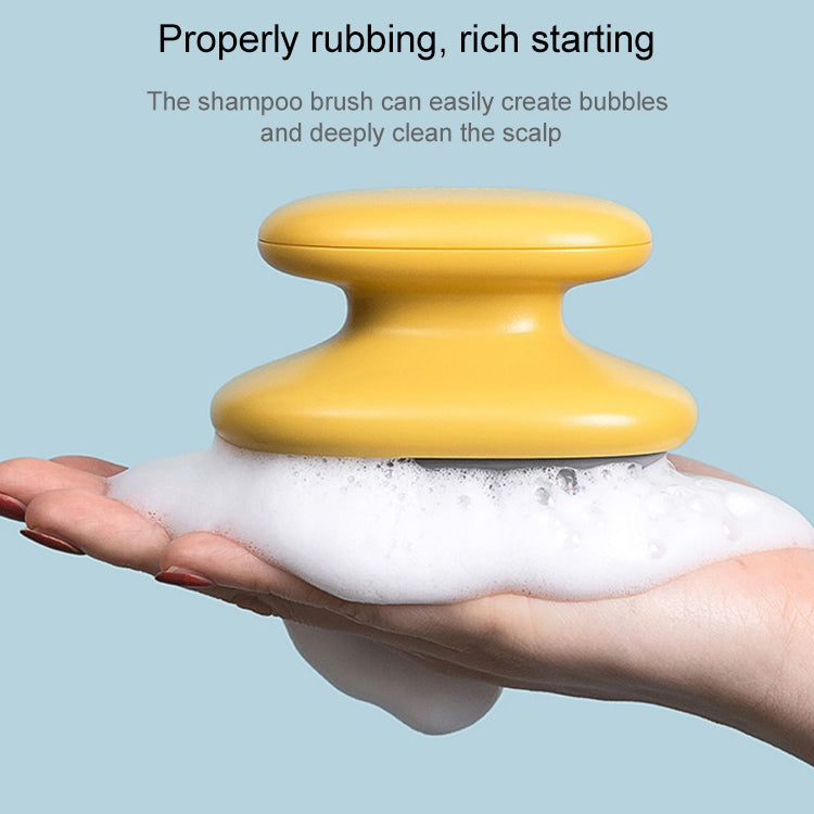 Yellow silicone shampoo massage brush resting on foamy lather in palm