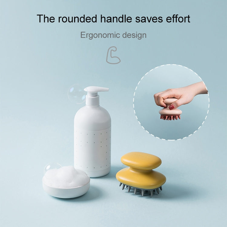 Yellow silicone scalp massage brush with rounded handle and gray bristles