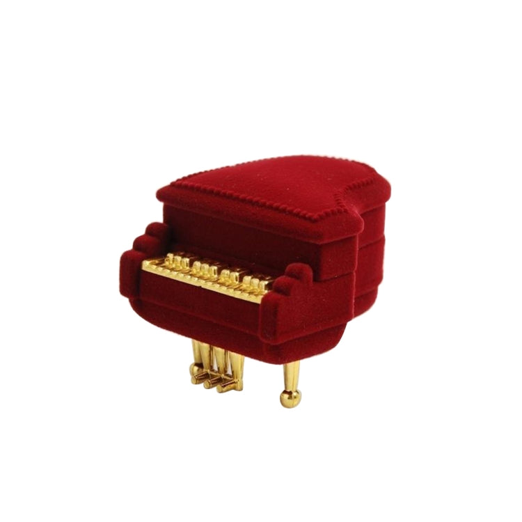 Red velvet piano-shaped jewelry box with gold front bar and four legs, closed lid