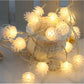 Warm white pine cone LED string lights with soft golden glow on a hanging wire