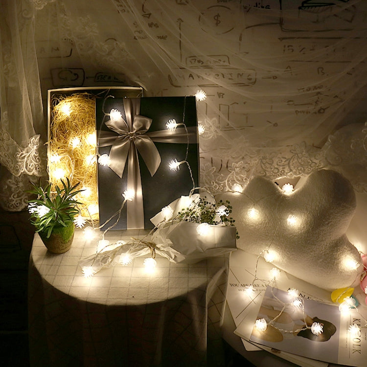 Warm white pine cone LED string lights with glowing bulbs on a thin outdoor-style wire