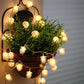 Warm white pine cone LED string lights draped around a wicker basket, glowing bulbs