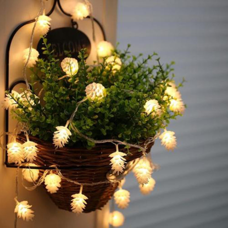 Warm white pine cone LED string lights draped around a wicker basket, glowing bulbs