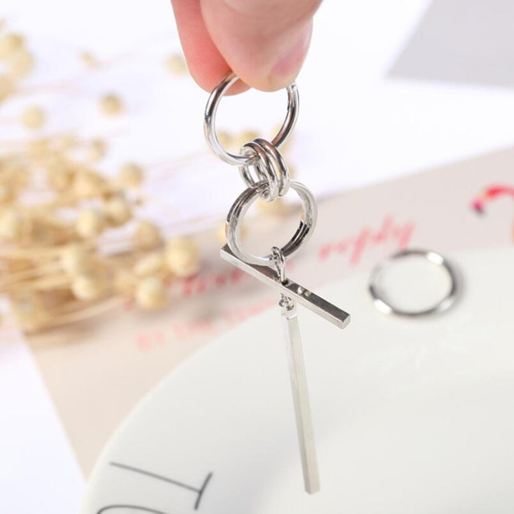 Hand holding silver-tone long asymmetric earrings with stacked hoops and a bar charm.