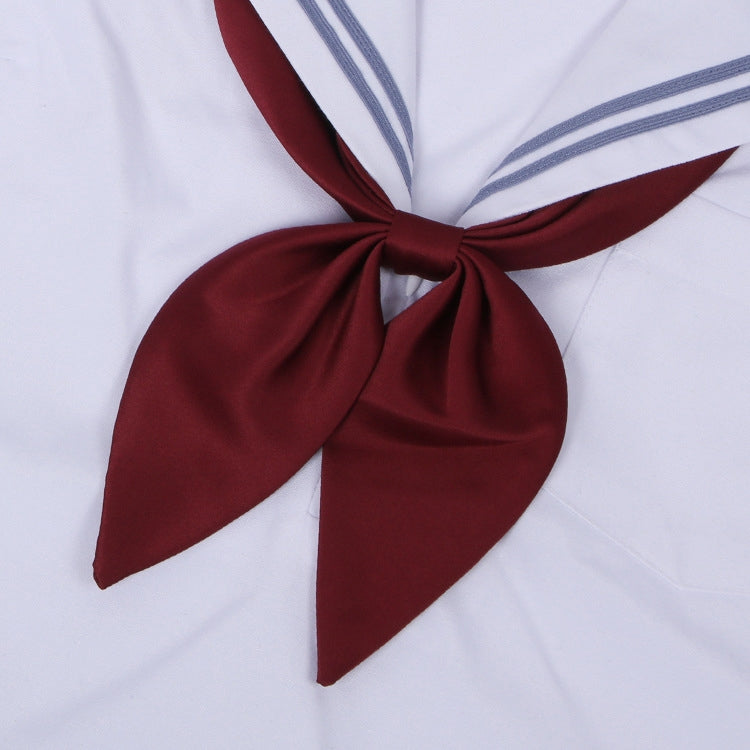 Goldfish-knot bow tie in claret red with a centered knot on a white shirt collar.