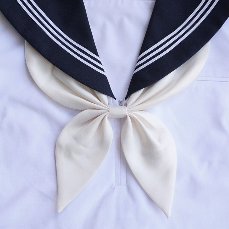 Goldfish-knot bow tie in white with dark navy ends and striped trim on a white shirt.