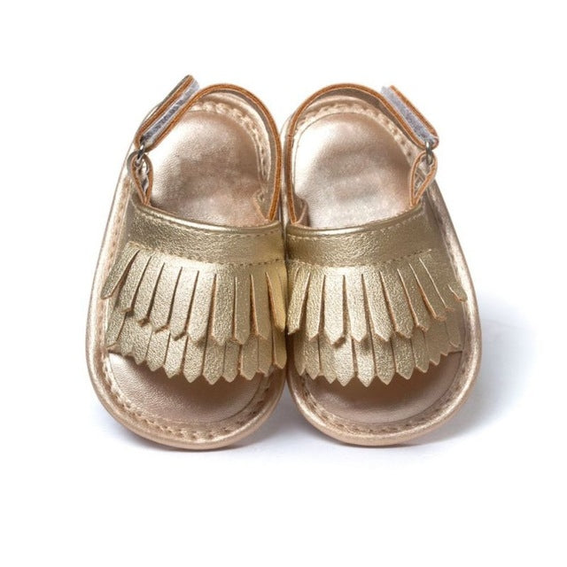 Gold metallic fringed baby sandals with hook-and-loop ankle straps, front view