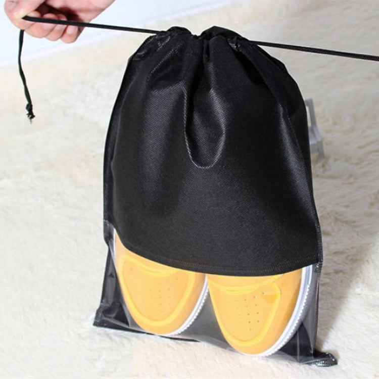 Black drawstring shoe storage bag holding yellow sneakers with transparent bottom