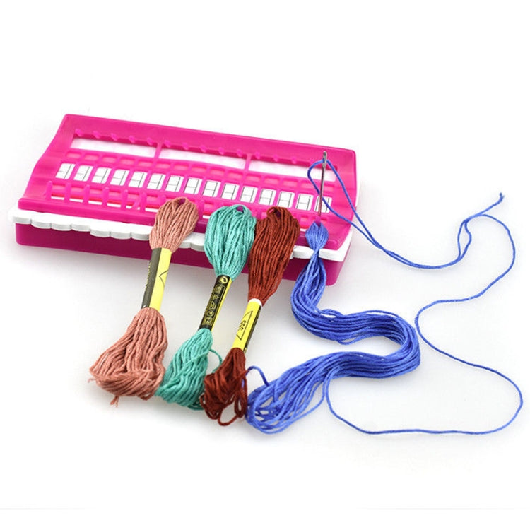 Pink cross-stitch thread organizer with embroidery floss skeins and paper template strip