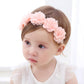 Pink flower baby headband with layered blossoms across elastic band