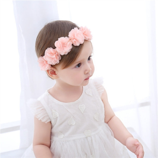 Pink rosette flower headband with side blossoms on toddler hair