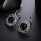 Round black stone drop earrings with ornate silver border and slender lever-back hooks