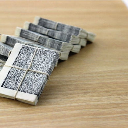 Miniature newspaper bundle toy with gray printed pages tied with twine