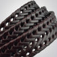 Close-up of black braided leather belt weave with glossy lacquer finish