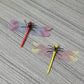 Dragonfly wall decor pair: red and yellow with translucent wings on wood surface