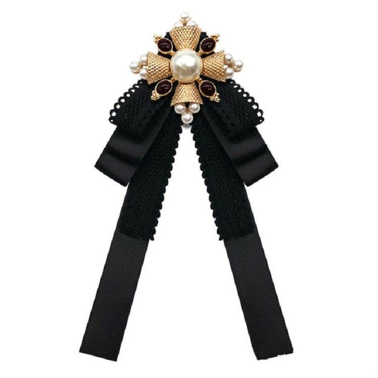 Black lace bow brooch with pearl center, gold accents, and layered ribbon tails