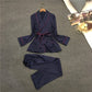 Navy silk-look pajama set with tie-belt robe top, red piping, and wide-leg trousers