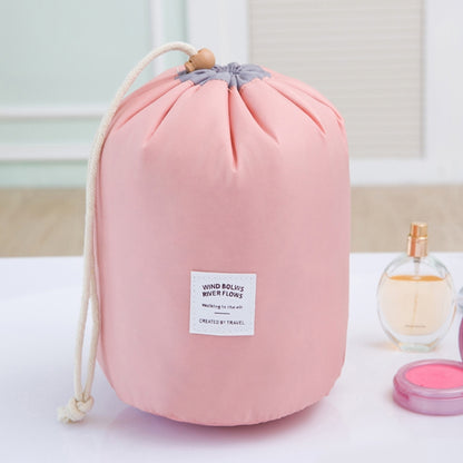 Pink cylindrical drawstring wash bag with braided rope handle and front label
