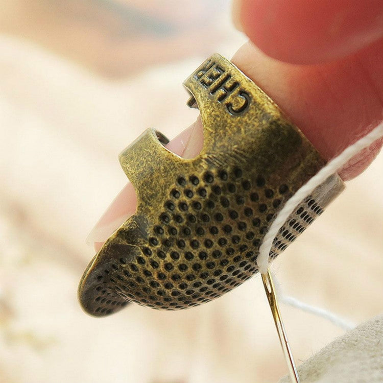 Close-up of adjustable metal sewing thimble, perforated gold-tone finger guard