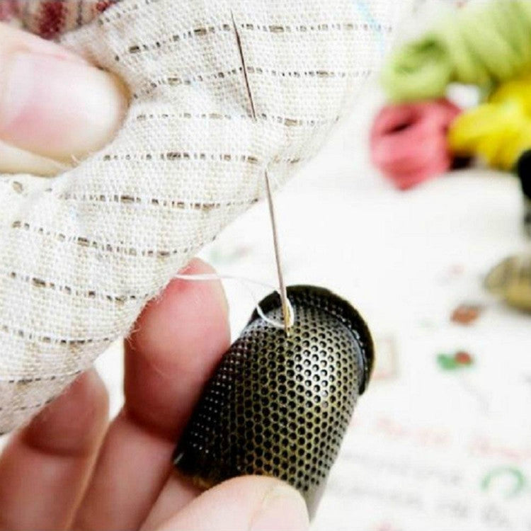 Hand holding a metal perforated sewing thimble while sewing fabric