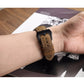 Brown leather watch band on wrist with black buckle and stitched strap
