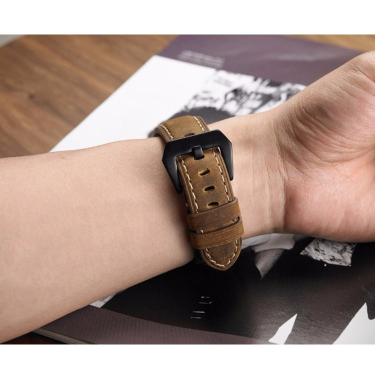 Brown leather watch band on wrist with black buckle and stitched strap