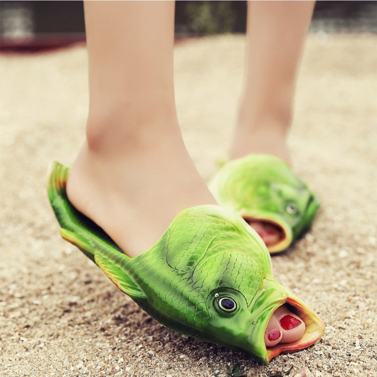 Close-up of green fish-shaped EVA sandals on sand, open-toe slip-on