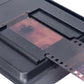 Dark gray film scanner slot holding a red 35mm negative strip