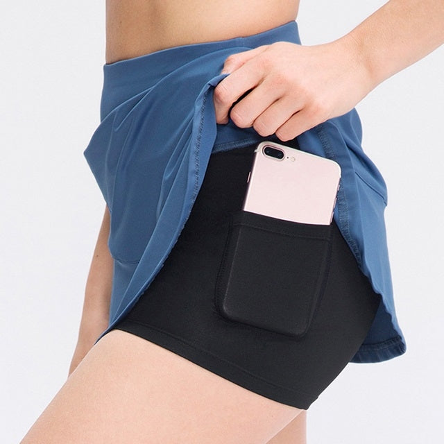 Blue athletic mini skirt with inner pocket holding a phone at the hip