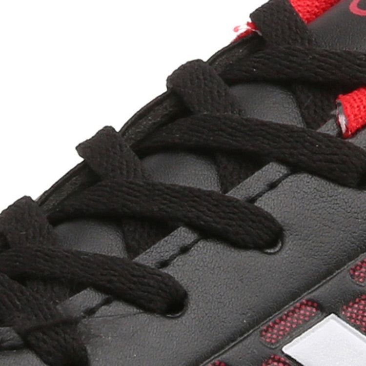 Close-up of black lace-up soccer shoe upper with textured grip and stitching