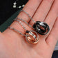Rose gold and black interlocking ring couple necklaces held in open palm with chains