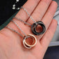 Black and rose gold interlocking ring couple necklaces in hand on silver chains