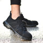 Black safety sneaker worn on foot with lace-up design and thick rubber sole